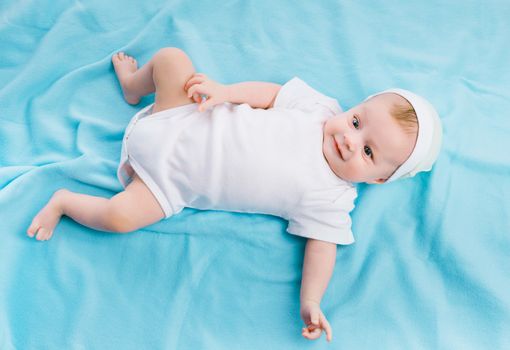 baby in cap lying on a blue blanket