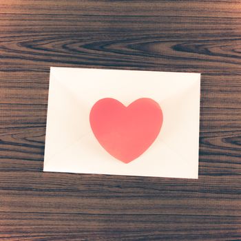 red heart with pink envelope on wooden background vintage style