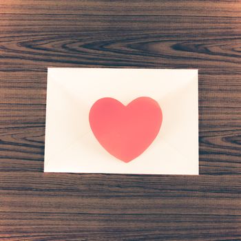 red heart with pink envelope on wooden background vintage style
