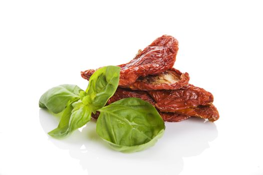 Sundried tomato with fresh basil herbs isolated on white background. Culinary italian eating.