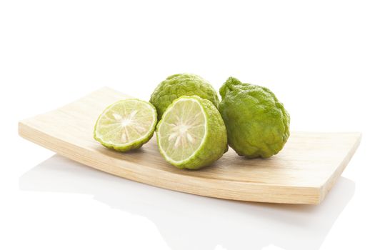 Bergamot oranges on wooden plate isolated on white background. Culinary asian tropical fruit eating.