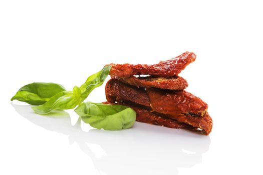 Sundried tomatos with fresh basil herbs isolated on white background. Culinary italian eating.