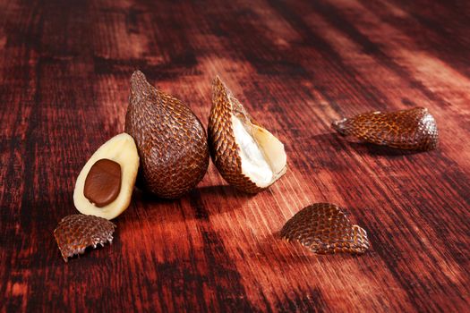 Delicious salak fruit on brown wooden textured background. Tropical fruit, rustic styles.