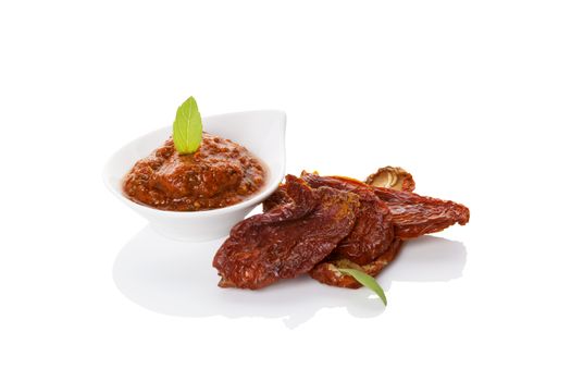 Dried tomatoes and red pesto with fresh basil leaf isolated on white background. Culinary eating, minimal contemporary styles. 