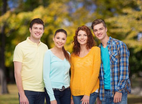 friendship, summer vacation, nature and people concept - group of smiling teenagers standing over green park background