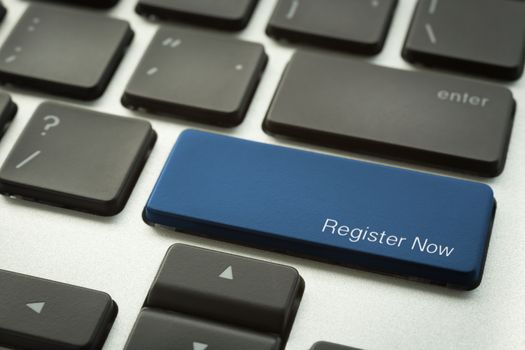 Close up laptop keyboard focus on a blue button with typographic word REGISTER NOW. E-business and internet marketing concepts.