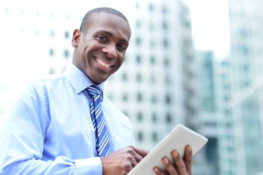 Smiling male corporate executive using his tablet pc