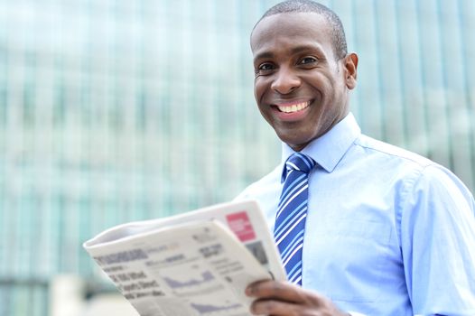 Corporate male smiling with magazine at outdoors