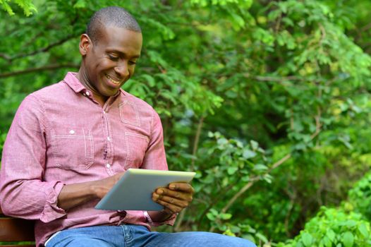Happy male using his tablet pc at outdoors