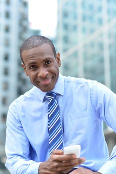 Corporate male sitting at outdoors with cell phone