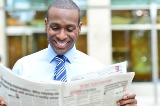 Happy male executive reading a newspaper