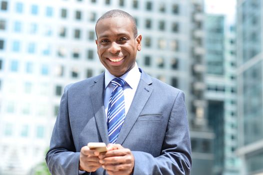 Smiling businessman posing with his mobile phone