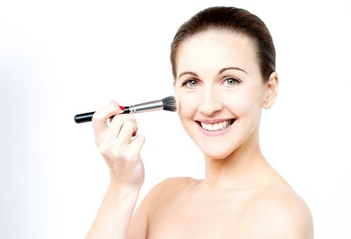 Topless woman applying foundation on face