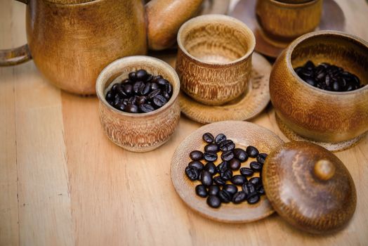 Coffee beans, cup of coffee and teapot on wooden desk. Set of cafe