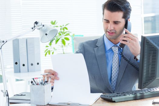 Professional businessman checking at his notebook while on the phone