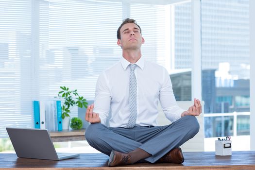 Zen businessman doing yoga meditation on the desk