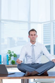 Zen businessman doing yoga meditation on the desk