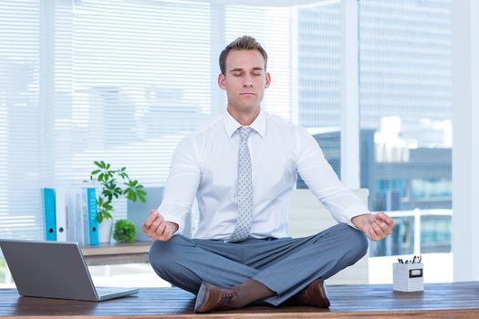 Zen businessman doing yoga meditation on the desk