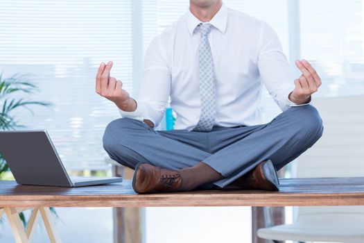 Zen businessman doing yoga meditation on the desk