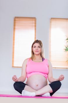 Pregnant woman doing yoga on exercise mat at home