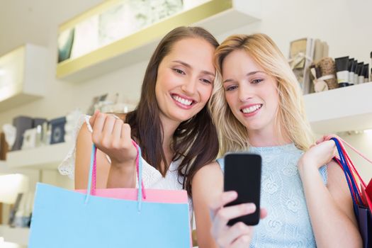 Happy women friends looking at smartphone in a beauty salon