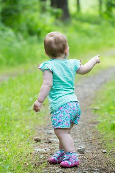 Cute Little girl walking away on the road ahead, looking back