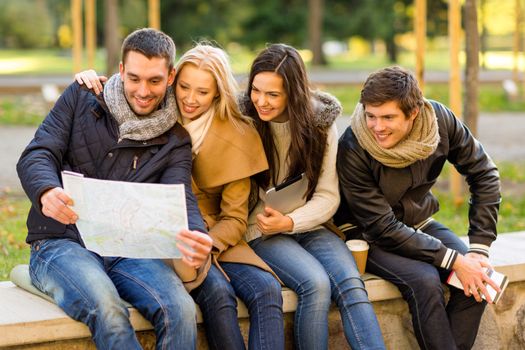 travel, vacation, people, tourism and friendship concept - group of smiling friends sitting with tablet pc computer city guide and map in park