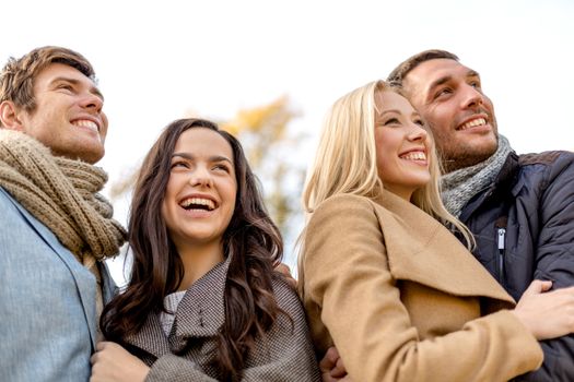 love, relationship, season, friendship and people concept - group of smiling men and women hugging in autumn park