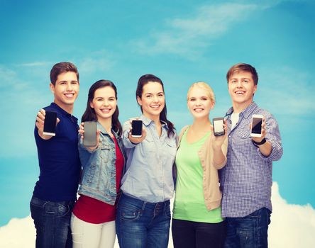 education and modern technology concept - smiling students showing blank smartphones screens over blue sky background
