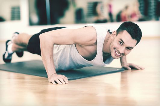 fitness, sport, training, gym and lifestyle concept - smiling man doing push-ups in the gym