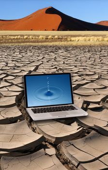 Laptop with pure water droplet on the screen on dry earth with sand dune. In the early morning sunlight near Sossusvlei in the Namib Desert in Namibia.