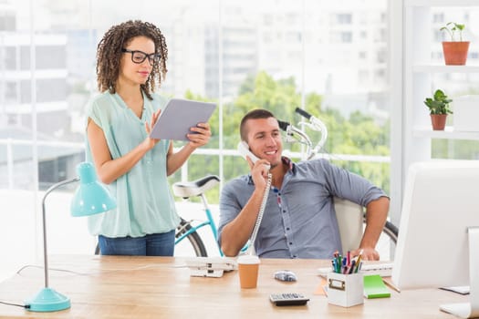 Young creative business colleagues on the phone and holding a tablet