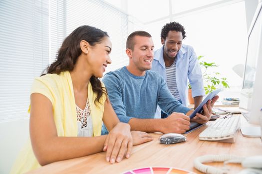 Smiling coworkers using tablet computer together in the office