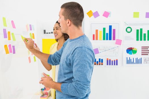 Smiling coworkers reading sticky notes in the office