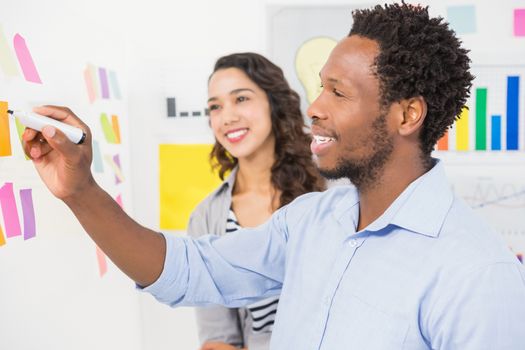 Young smiling creative business people writing on sticky notes