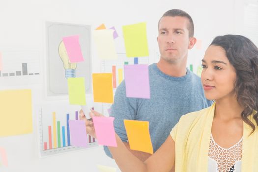 Concentrated coworkers pointing sticky notes in the office