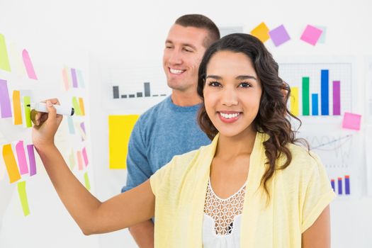 Portrait of smiling coworkers writing on sticky notes in the office