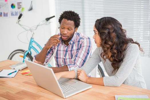 Young business people in the office talking on the phone and typing on the laptop