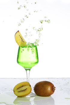 Stemmed champagne glass with kiwi liquor splashing out, isolated on white background