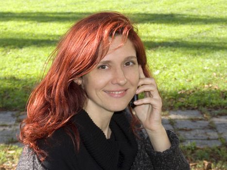 beautiful red head woman with cell phone, outdoor portrait