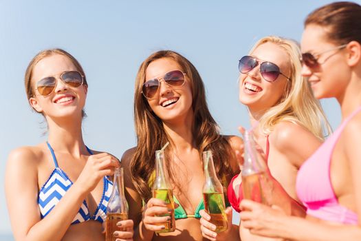 summer vacation, holidays, travel and people concept - group of smiling young women sunbathing and drinking on beach