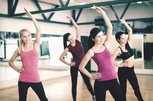 fitness, sport, training, gym and lifestyle concept - group of smiling people stretching in the gym