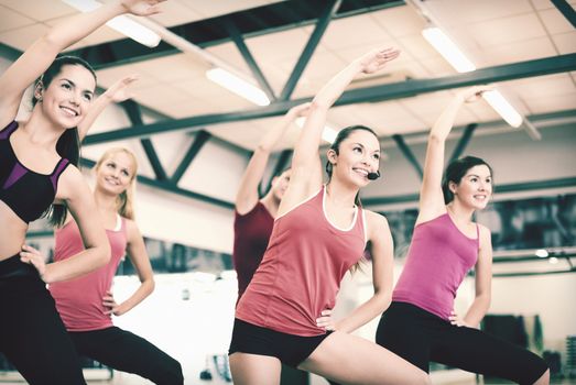 fitness, sport, training, gym and lifestyle concept - group of smiling people stretching in the gym