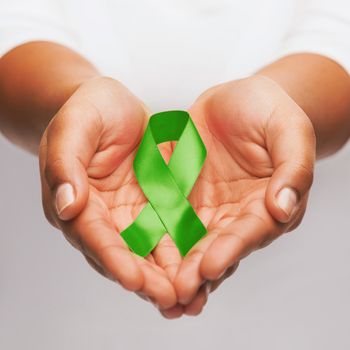 healthcare and medicine concept - female hands holding green organ transplant awareness ribbon