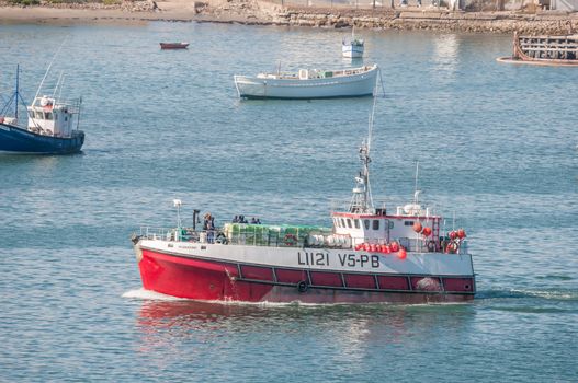 LUDERITZ, NAMIBIA - JUNE 15, 2011: A hake fishing vessel leaving Luderitz harbor on a fishing trip. Fishing is the biggest industry in Luderitz