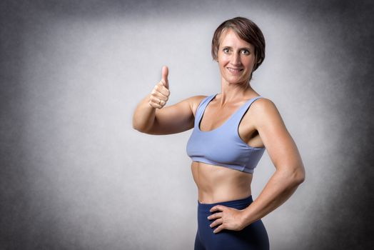 Middle aged handsome woman in sportswear with thumb up