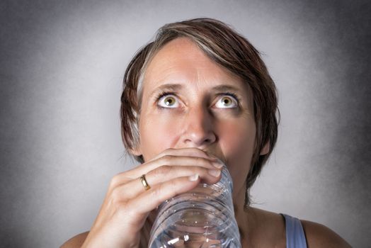 Image of middle aged handsome woman drinking water from a bottle