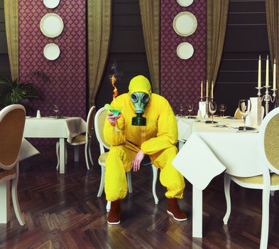 the man in a protective coverall sitting in an empty restaurant with a drink. Photo combination creative concept