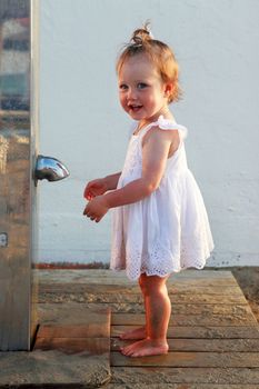 Little girl on the beach near the shower