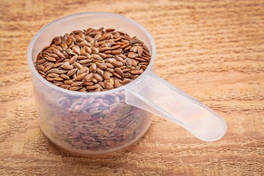 measuring scoop of brown flax seeds against textured cedar wood